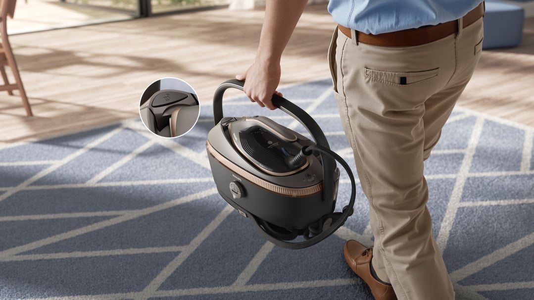 Man carrying a Philips PerfectCare Steam Generator 8000 Series iron across a rug