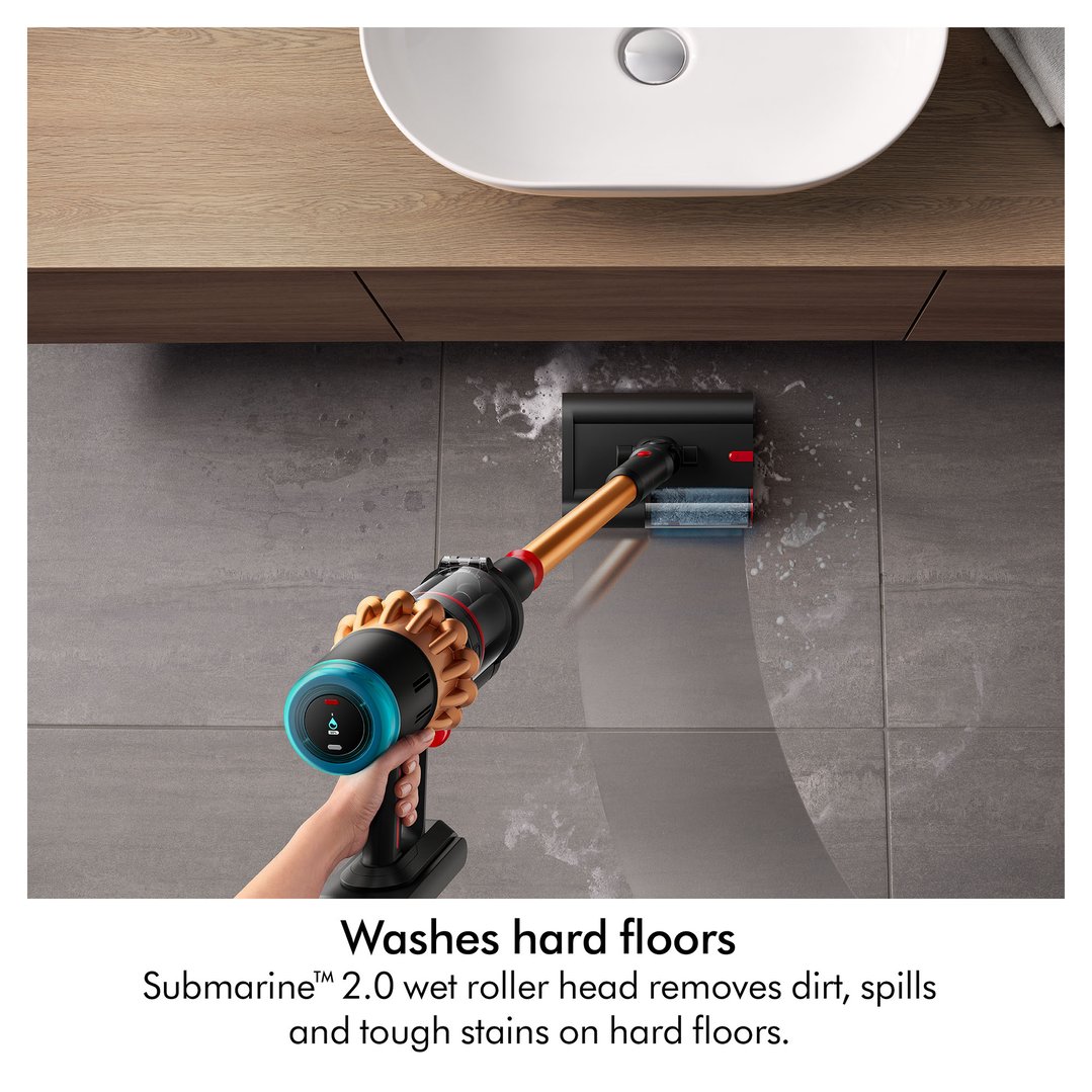 Hand holding a Dyson handStickVacuum cleaning a tiled floor in a bathroom