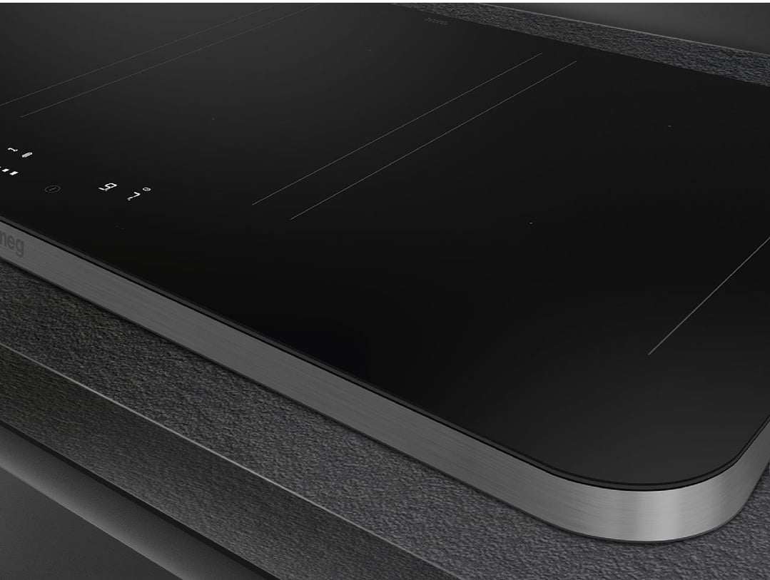 Close-up of a black induction cooktop with a stainless steel trim