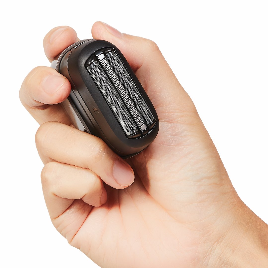 Hand holding a black compact 3-blade shaver against a white background