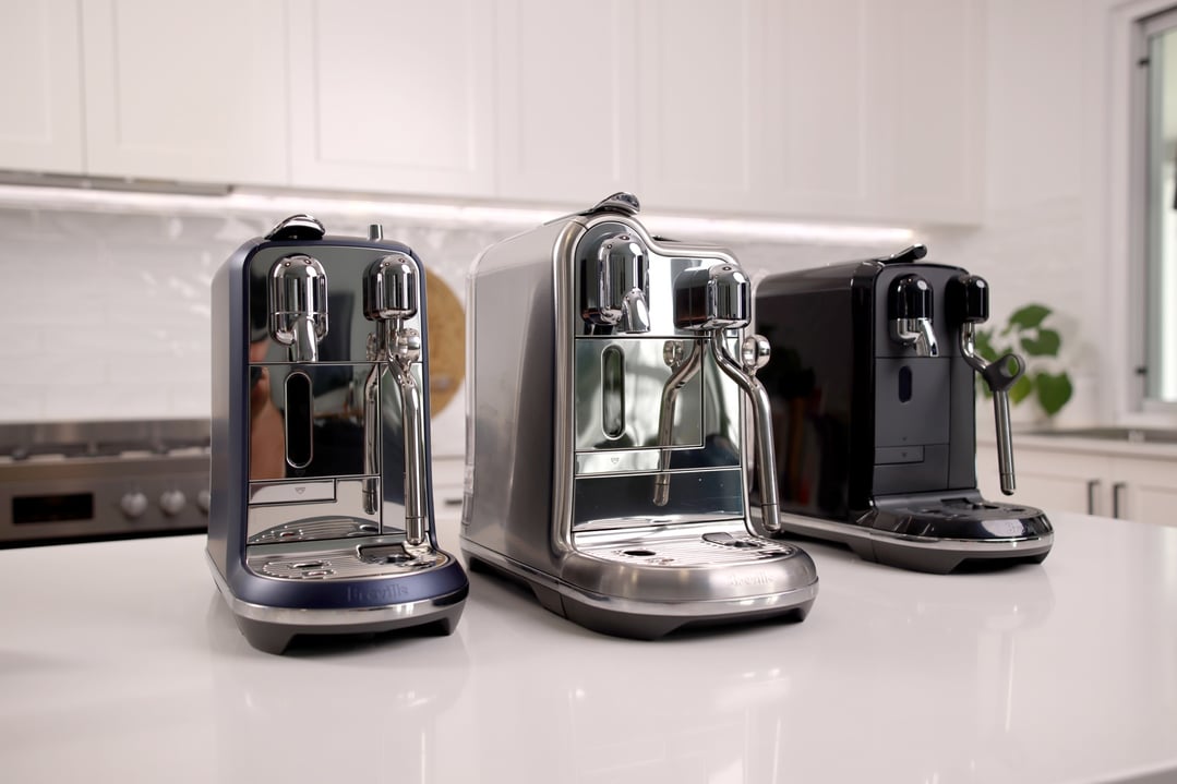 Three Nespresso Creatista Plus coffee machines on a white kitchen counter