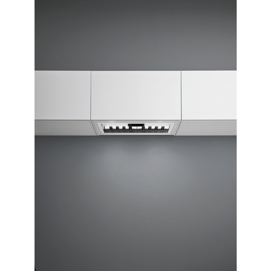 Under cupboard rangehood integrated into white kitchen cabinetry with dark grey wall