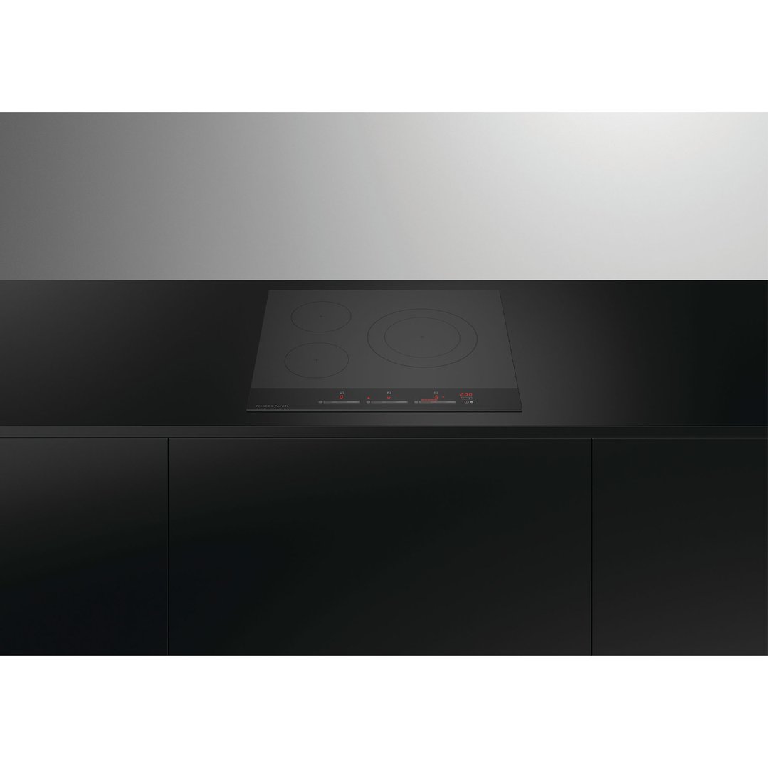 Black induction cooktop with red display lights built into a dark kitchen counter