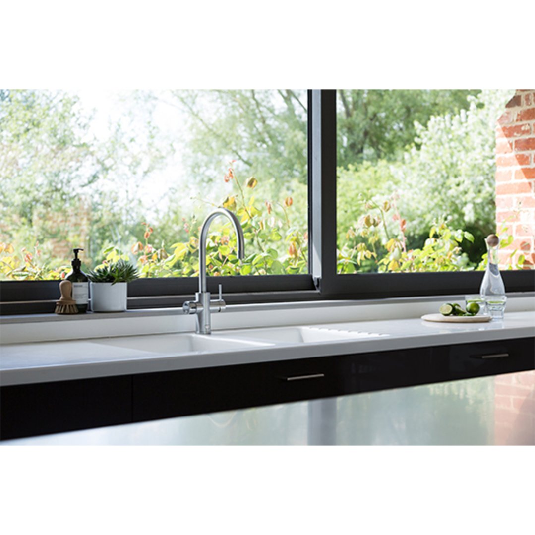 Brushed nickel tap installed in a kitchen sink with a window view