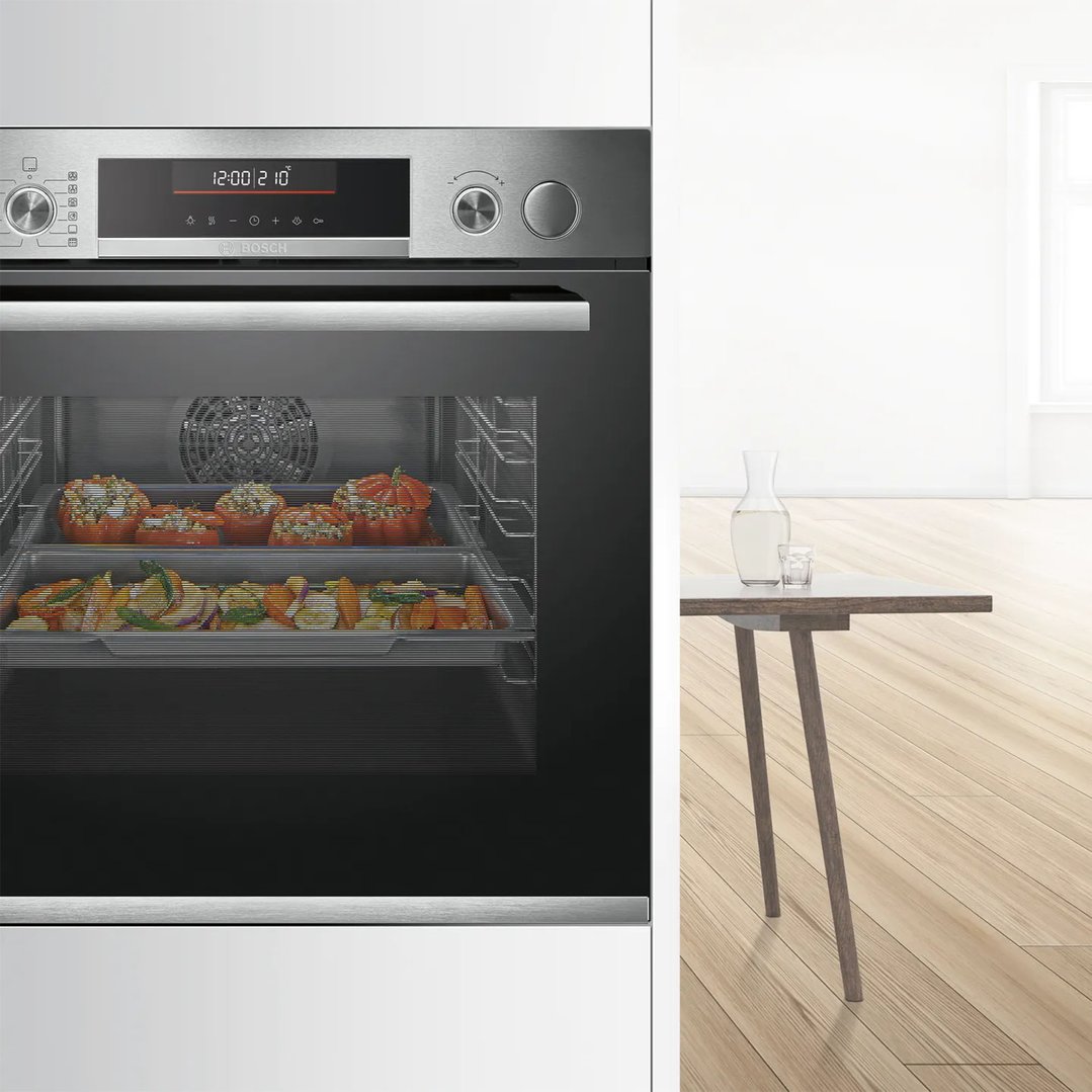 Built-in oven with food cooking inside, next to a table with a jug