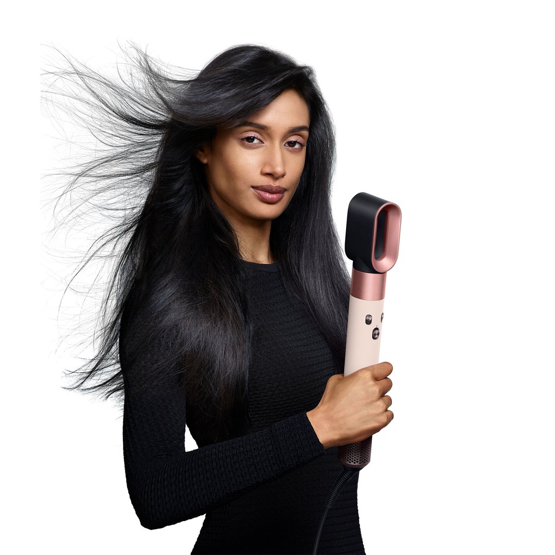 Woman with long dark hair holding a Dyson Airwrap multi-styler and dryer