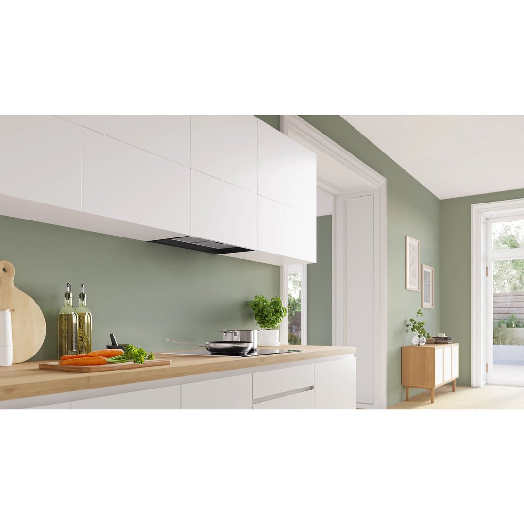 Integrated rangehood in a modern kitchen with light green walls and wooden countertop