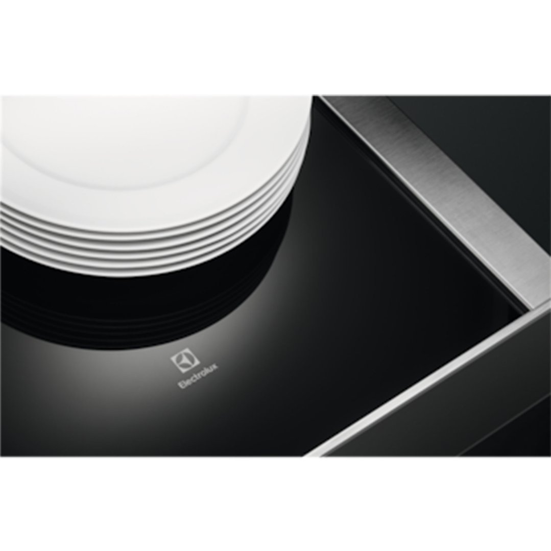 Stack of white plates on a black warming drawer with Electrolux logo