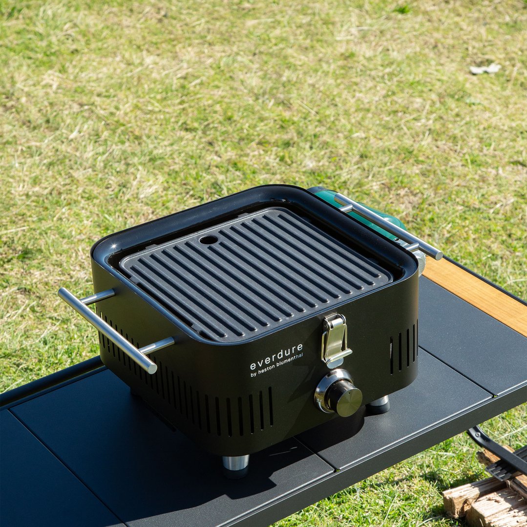 EVERDURE Pro Flame 360 Solid Plate on a black table outdoors with grass background