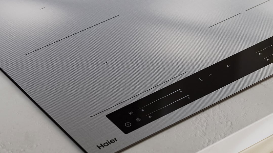 Close up of a Haier induction cooktop with controls on a white benchtop