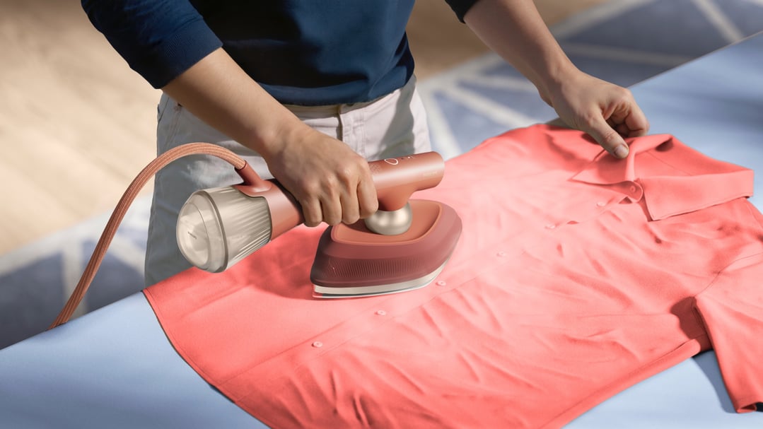 Person ironing a coral shirt with a Philips OneTurn Hybrid Iron & Steamer