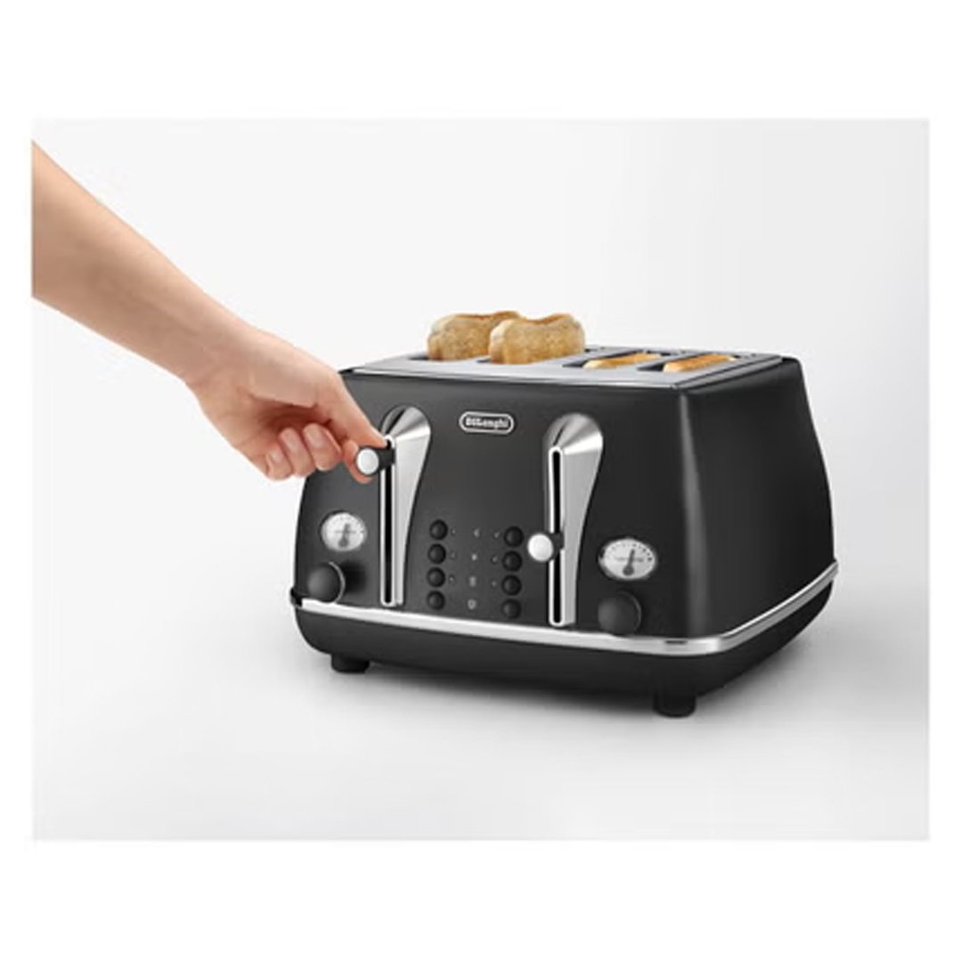 Hand adjusting settings on a black 4-slice toaster with toast inside