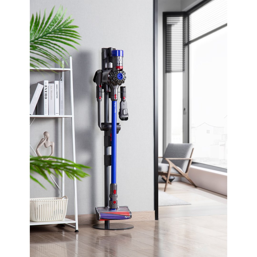 A Dyson cordless vacuum on a floor stand in a modern living room