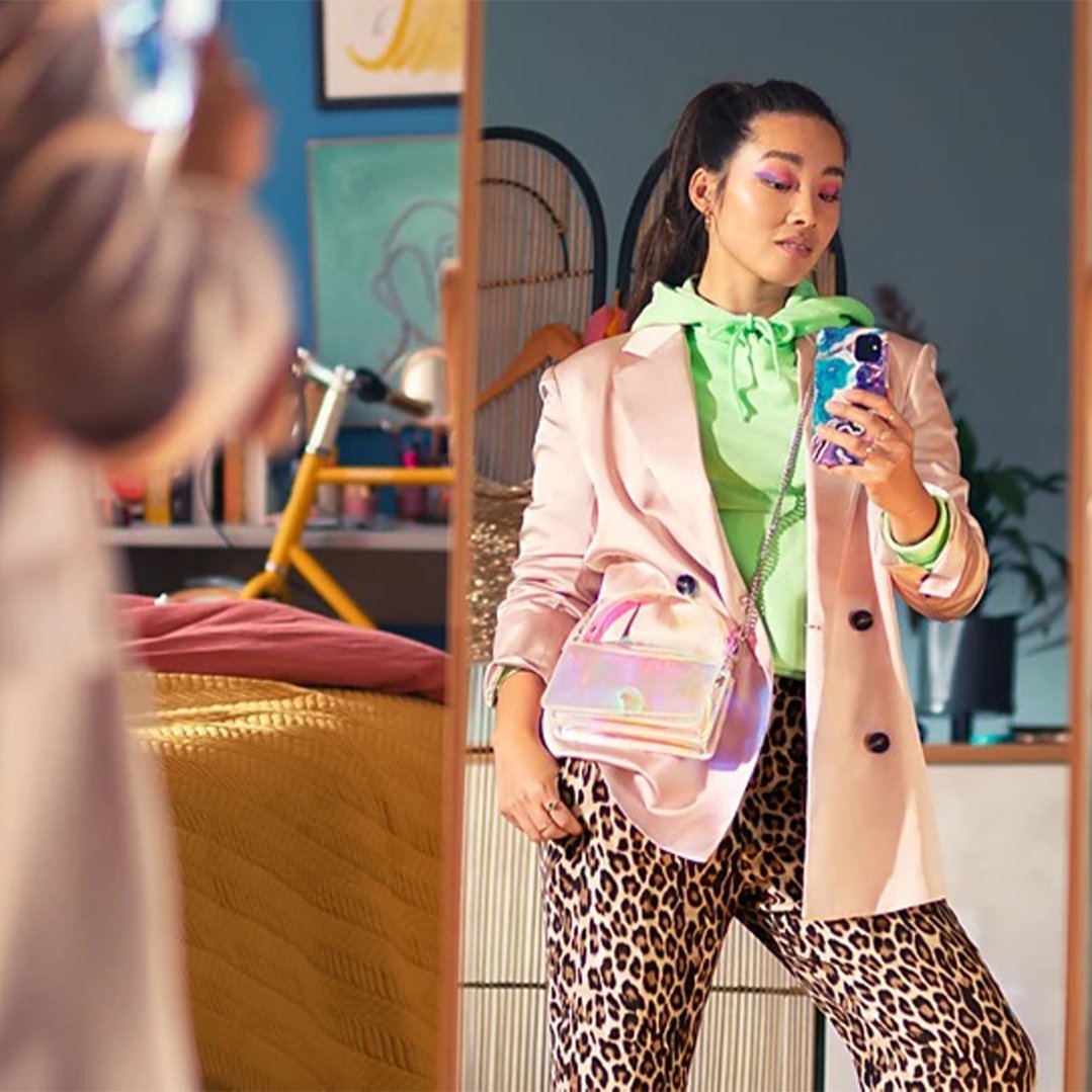 Woman taking a selfie in a mirror, wearing a blazer and leopard print pants