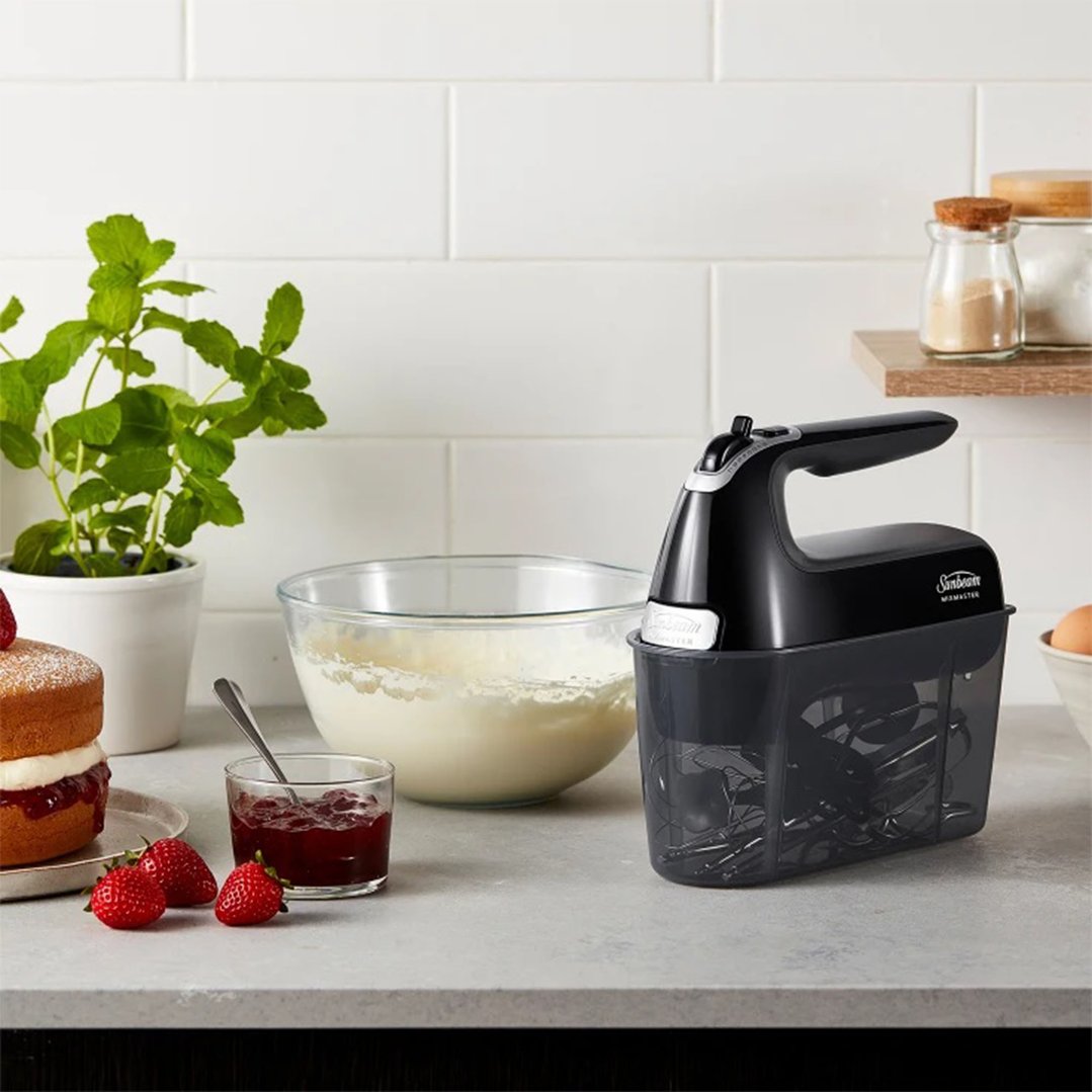 Black Sunbeam Mixmaster Hand Mixer Pro on a kitchen counter with baking ingredients