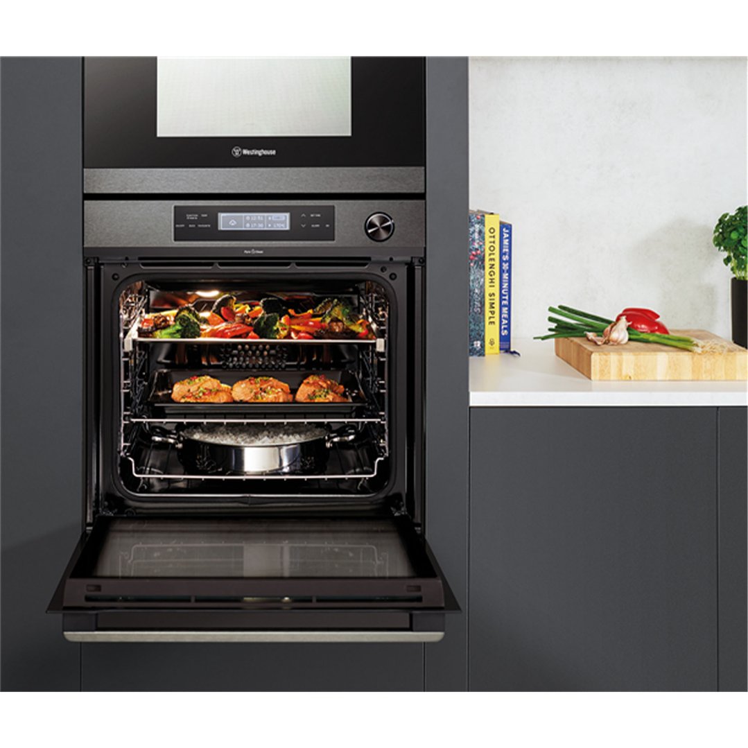 Built-in oven with door open, cooking food on multiple racks in a kitchen