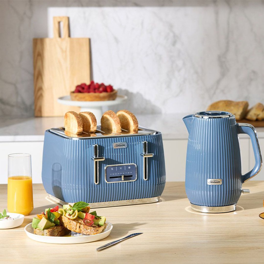 Blue toaster and kettle on a wooden counter with breakfast items