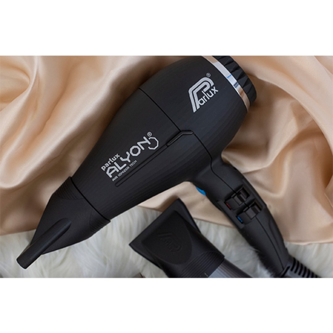 Black Parlux Alyon hair dryer and nozzle on a cream and white fabric background