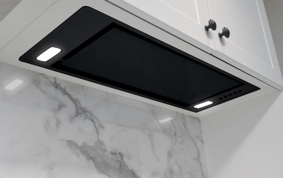 Undermount rangehood with lights on, installed above a marble backsplash