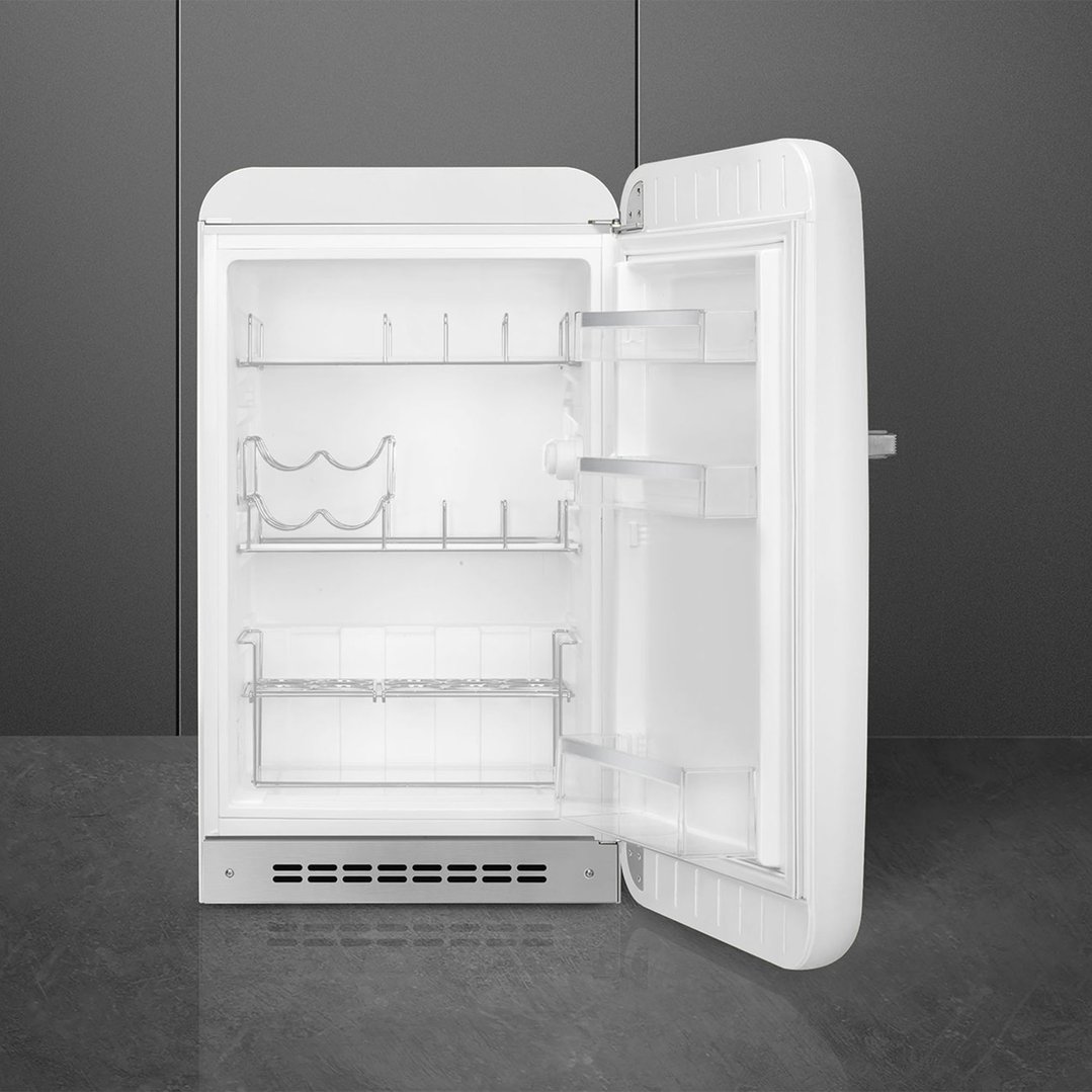 White Smeg retro refrigerator with door open, showing interior shelves