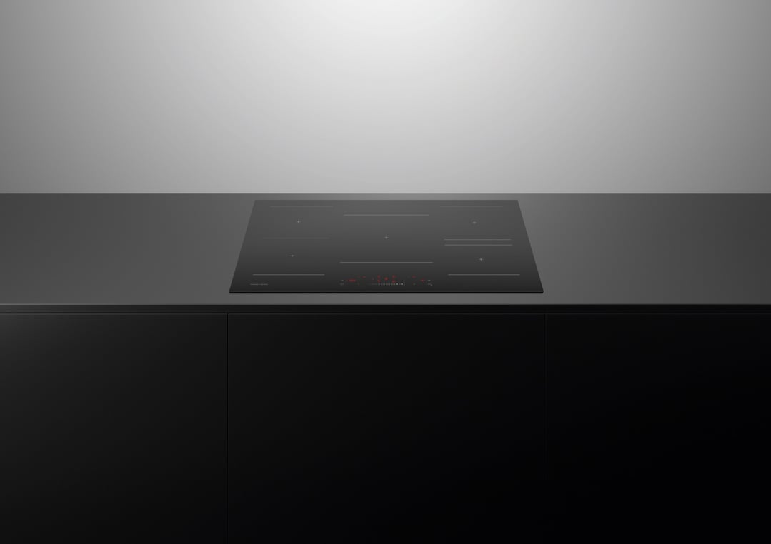 Black induction cooktop with red digital display on a dark countertop in a kitchen