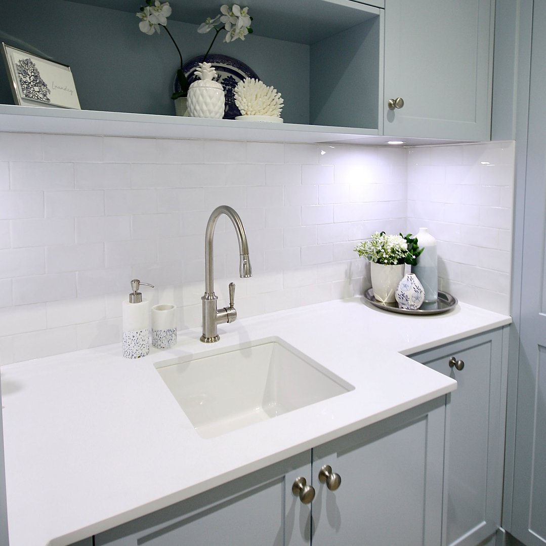 White fireclay sink with a faucet in a light blue laundry room