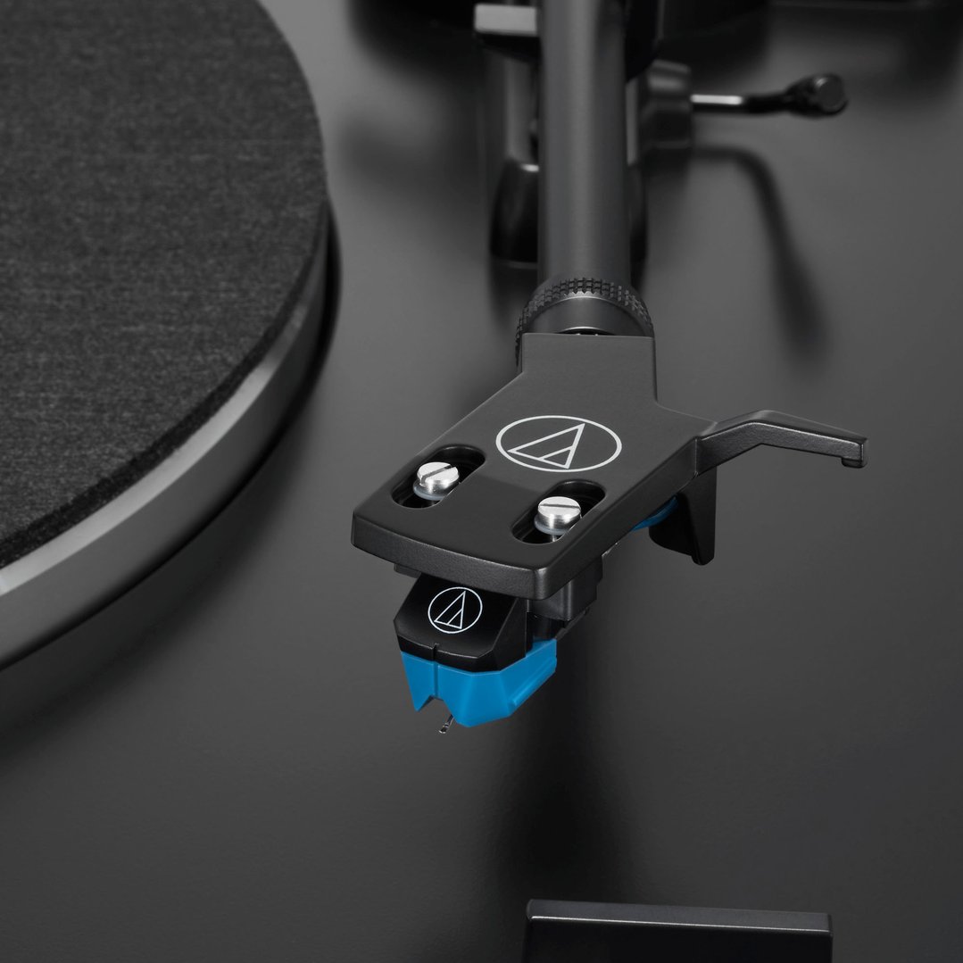 Close-up of a black turntable's tonearm and cartridge with a blue stylus