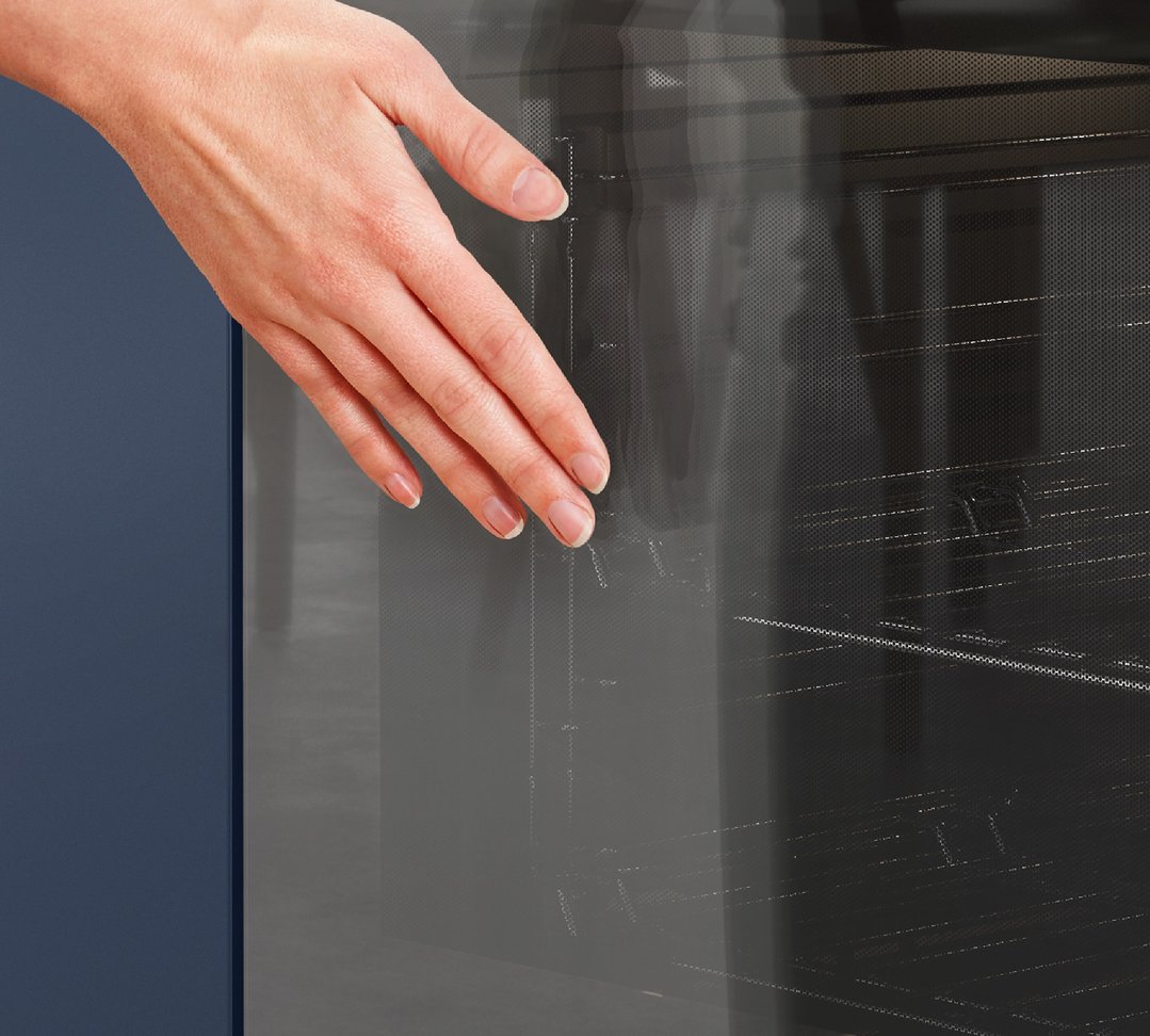 Hand reaching into a Westinghouse oven with a dark blue cabinet beside it