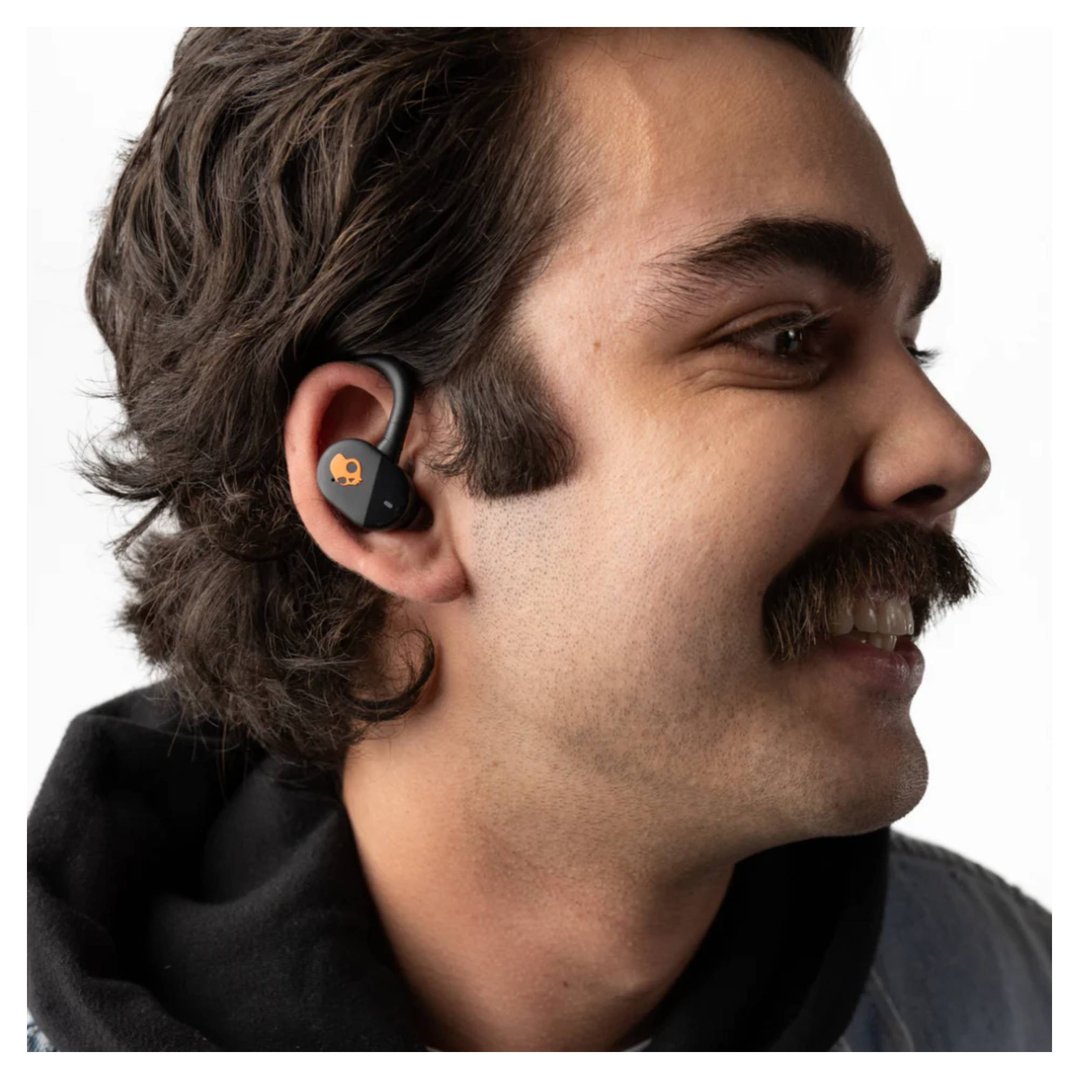 Man wearing a black and orange Skullcandy Push Play Active TWS headset