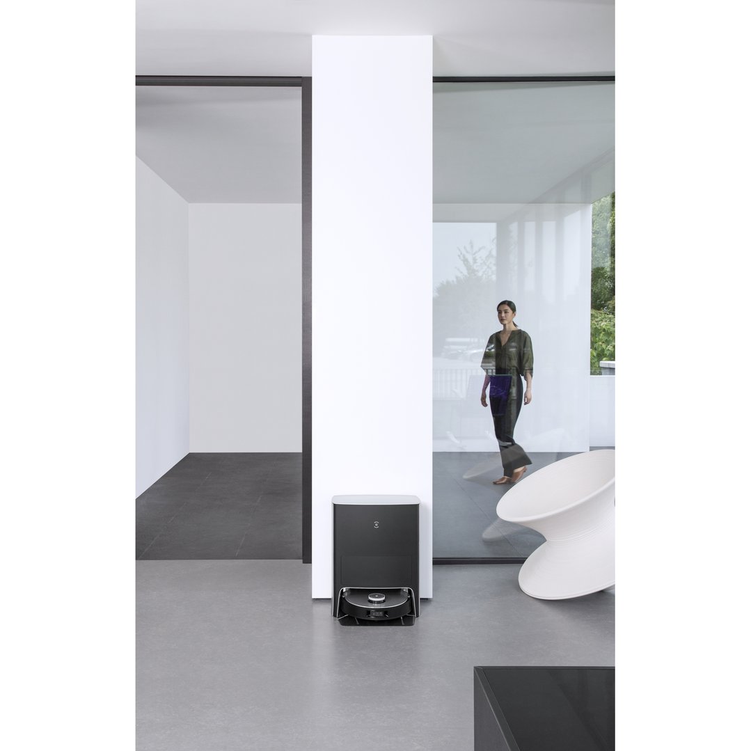 DEEBOT X1 OMNI robotic vacuum in a modern room with a woman walking by