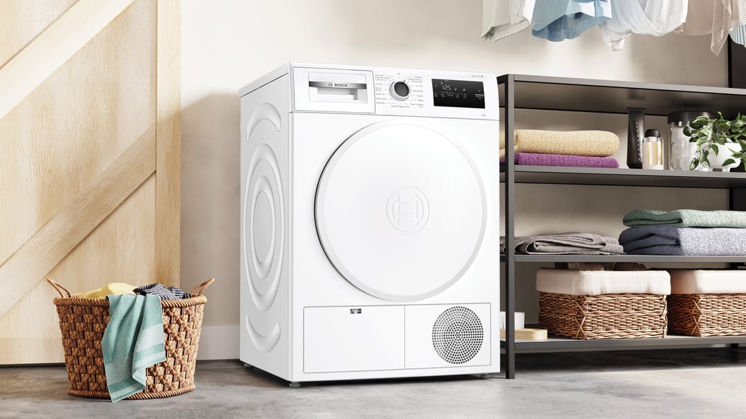White Bosch heat pump tumble dryer in a laundry room setting