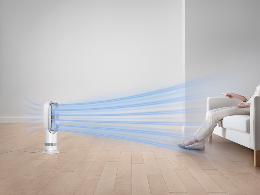 Dyson fan heater blowing air towards a person sitting on a white sofa