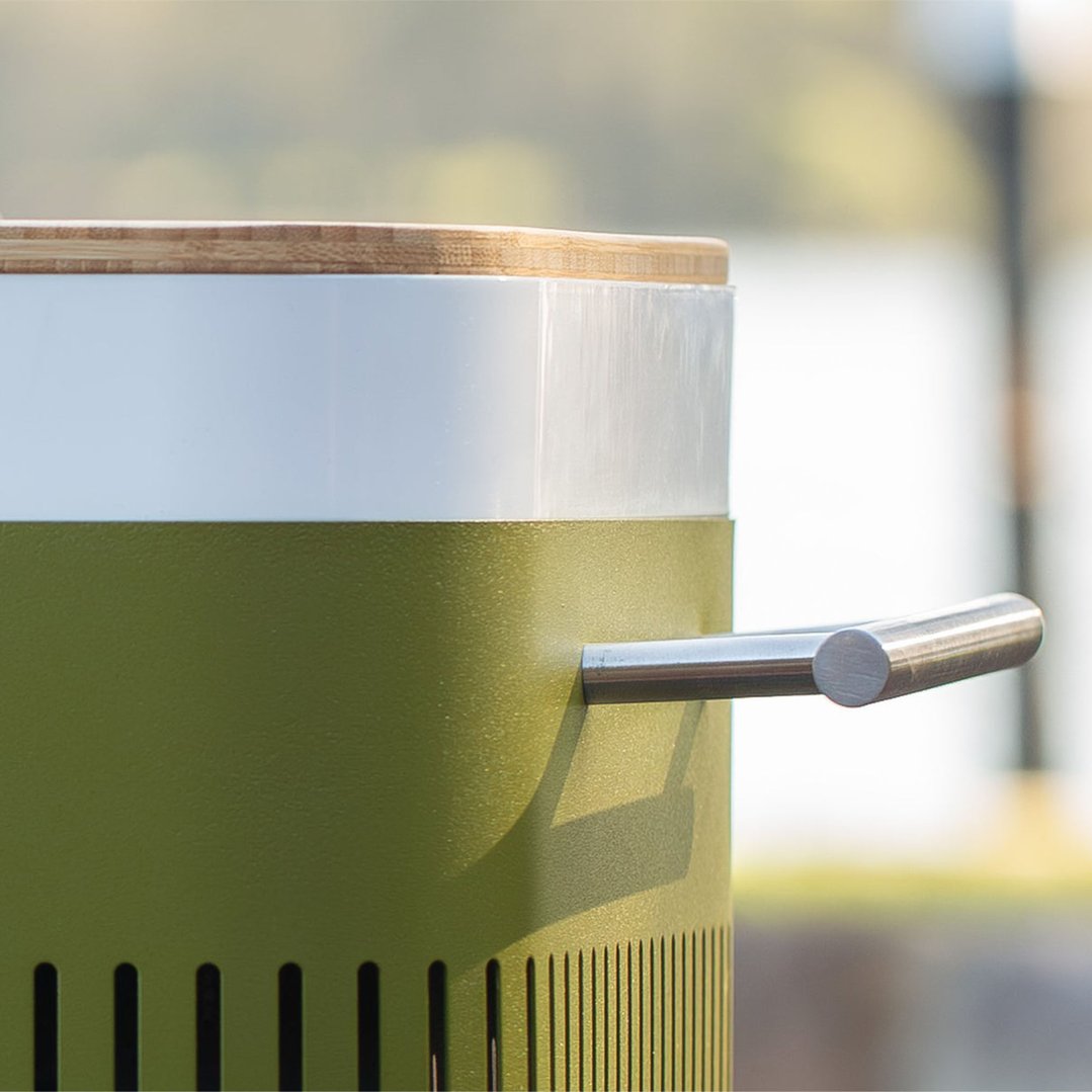 Close up of a portable charcoal BBQ with a wooden lid and metal handle