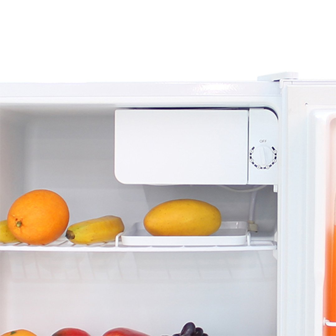 Open white bar fridge with fruit on shelves, showing temperature dial