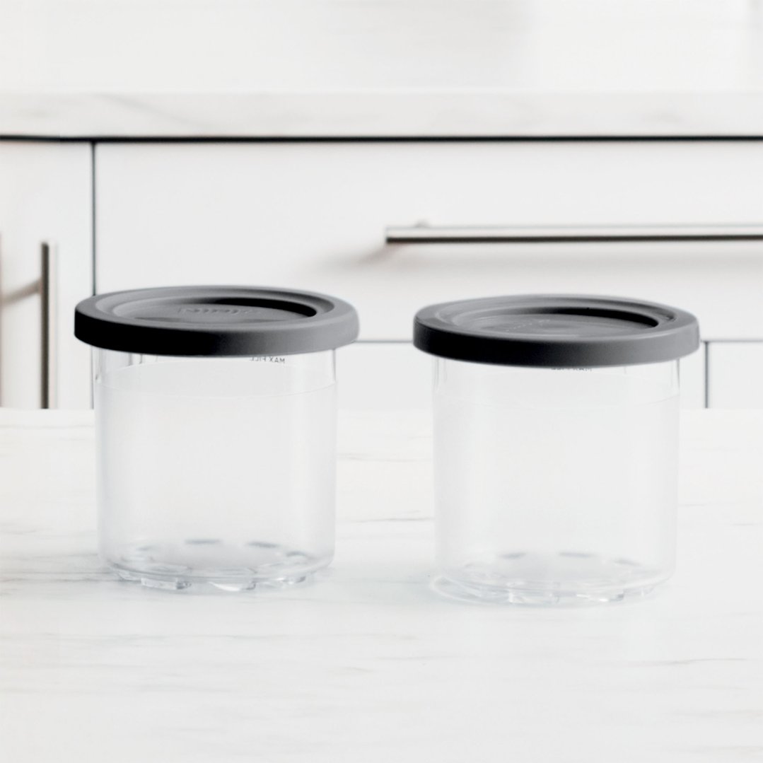 Two Ninja Creami tubs with lids on a white countertop in a kitchen