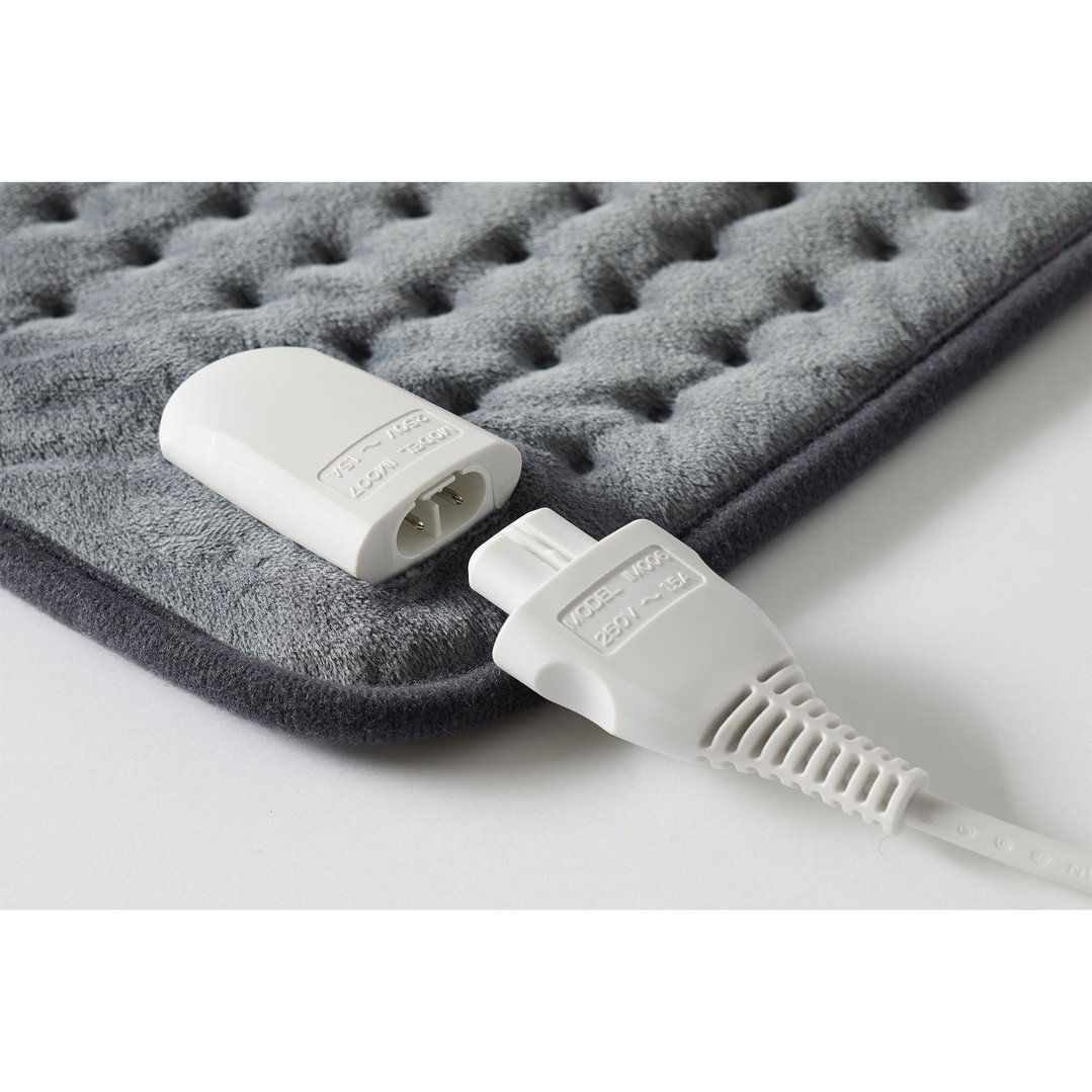 Close up of a gray heating pad with its power cord disconnected