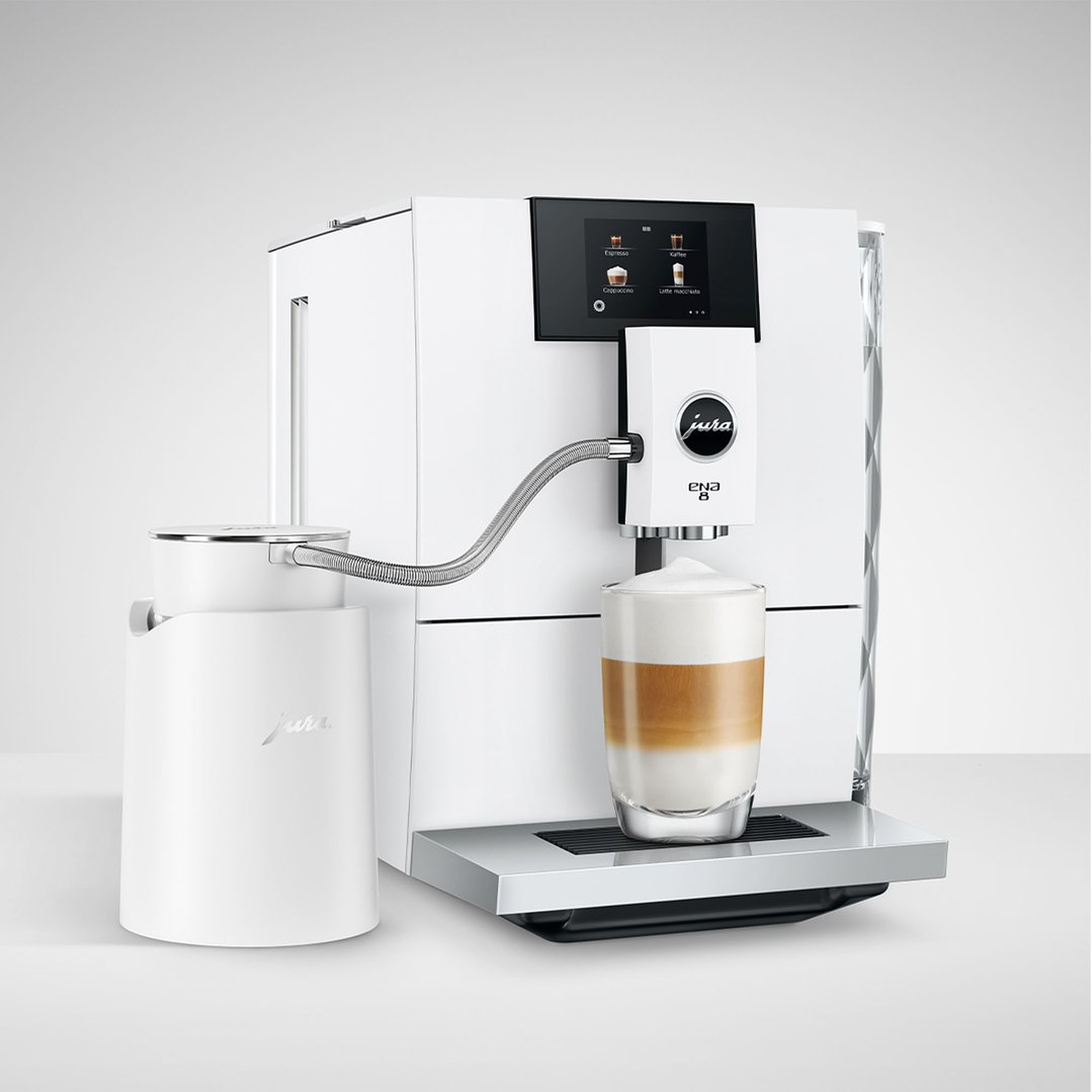 White JURA coffee machine and milk carafe making a latte macchiato