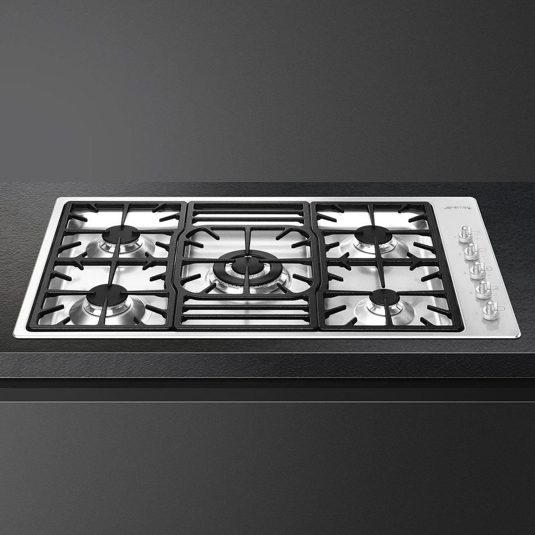 Stainless steel gas cooktop with five burners and controls on a dark countertop