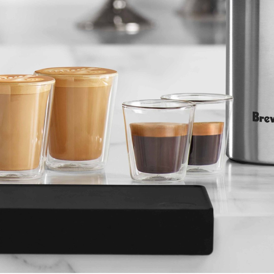Four dual wall glasses with coffee and espresso on a marble countertop
