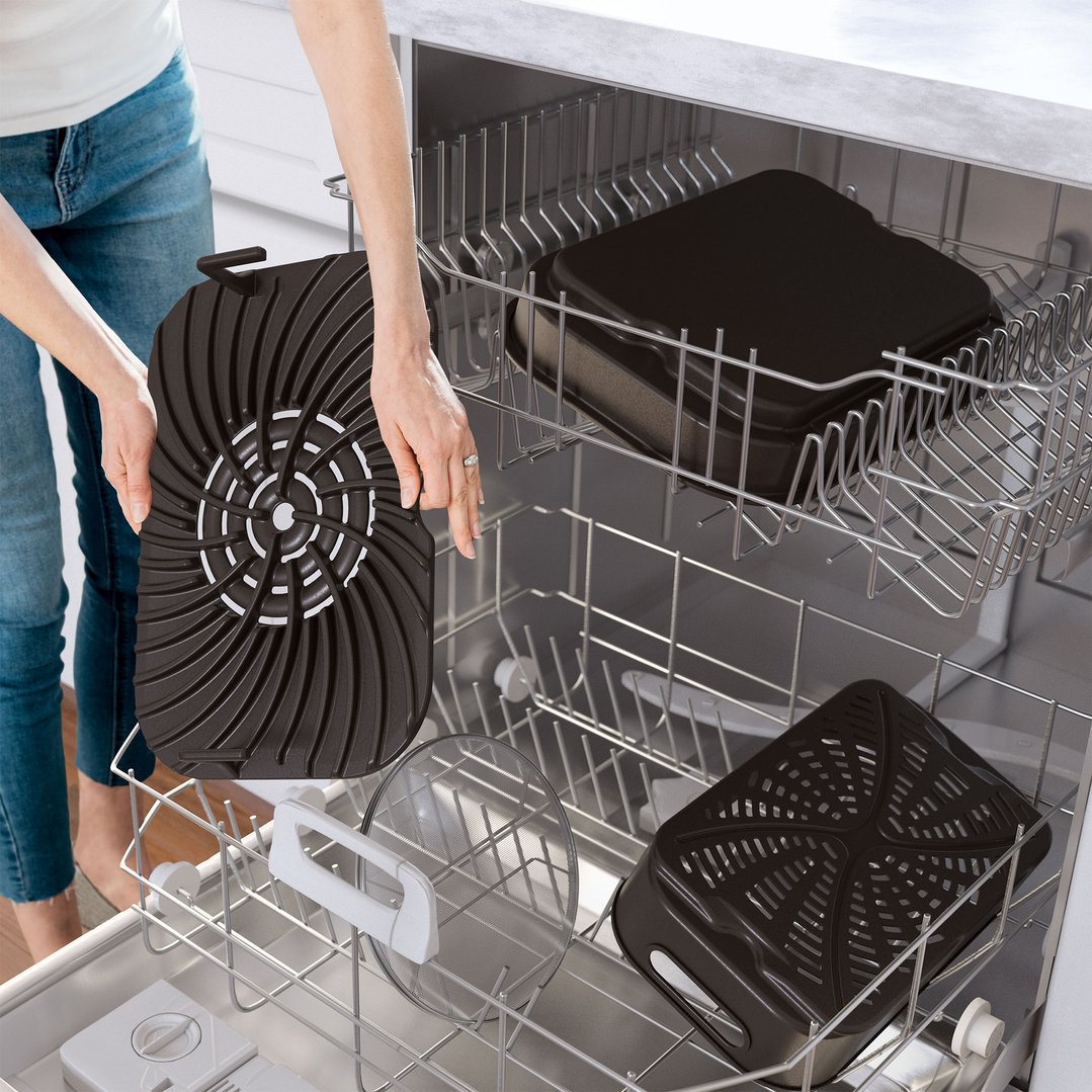 Person loading deep fryer components into the bottom rack of a dishwasher