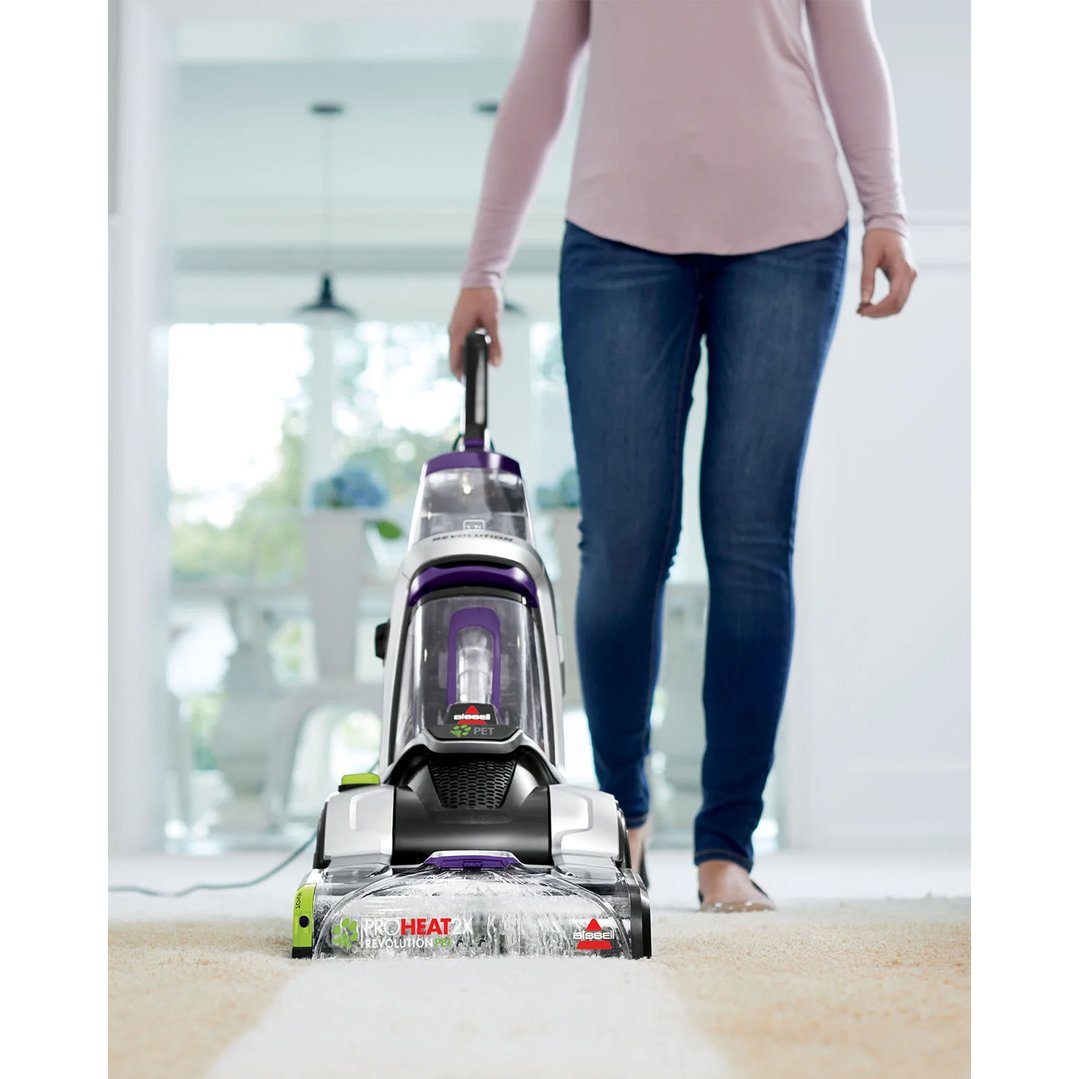 Woman using a BISSELL ProHeat 2X Revolution Pet upright carpet washer on a carpet