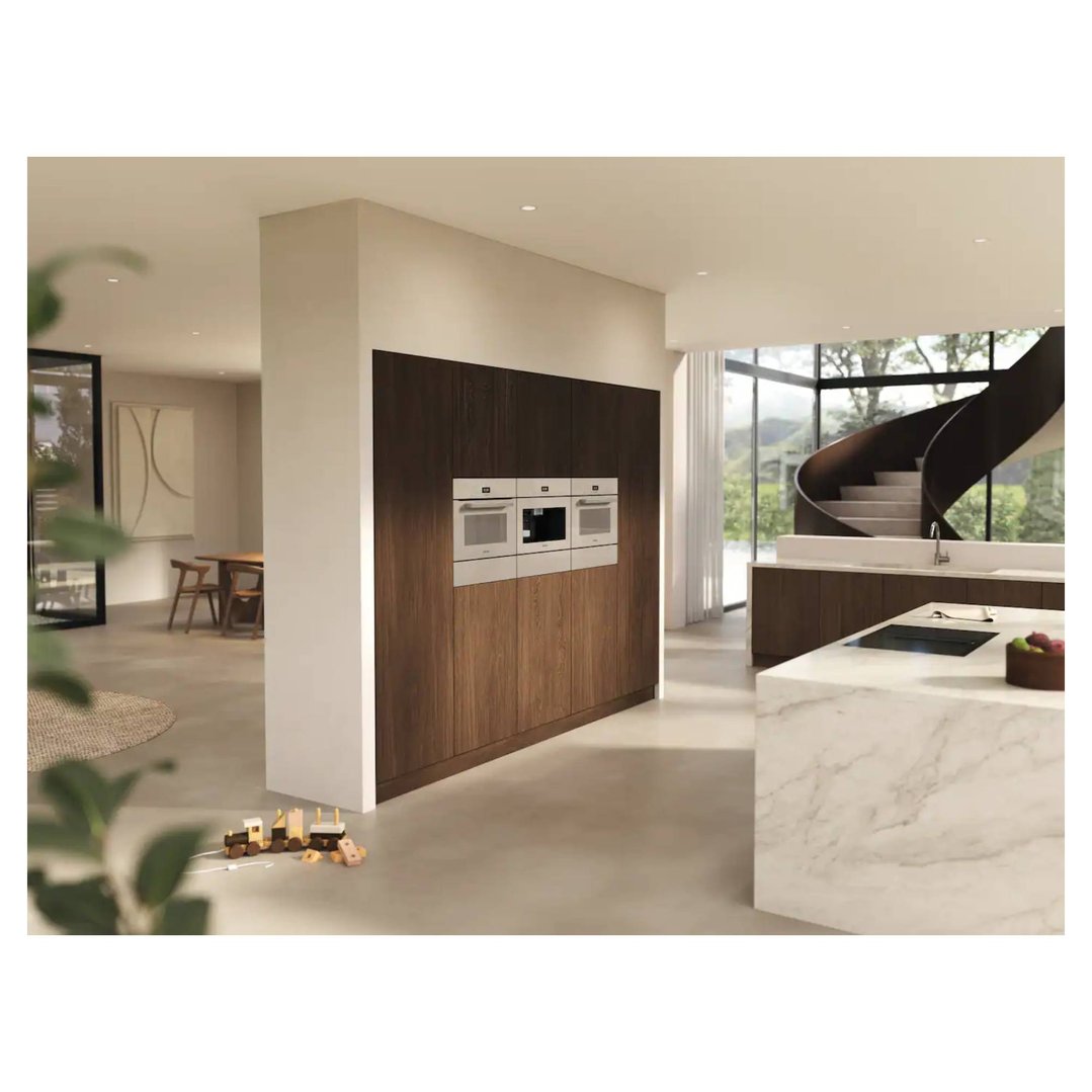 Three ovens built into dark wood cabinetry in a modern kitchen