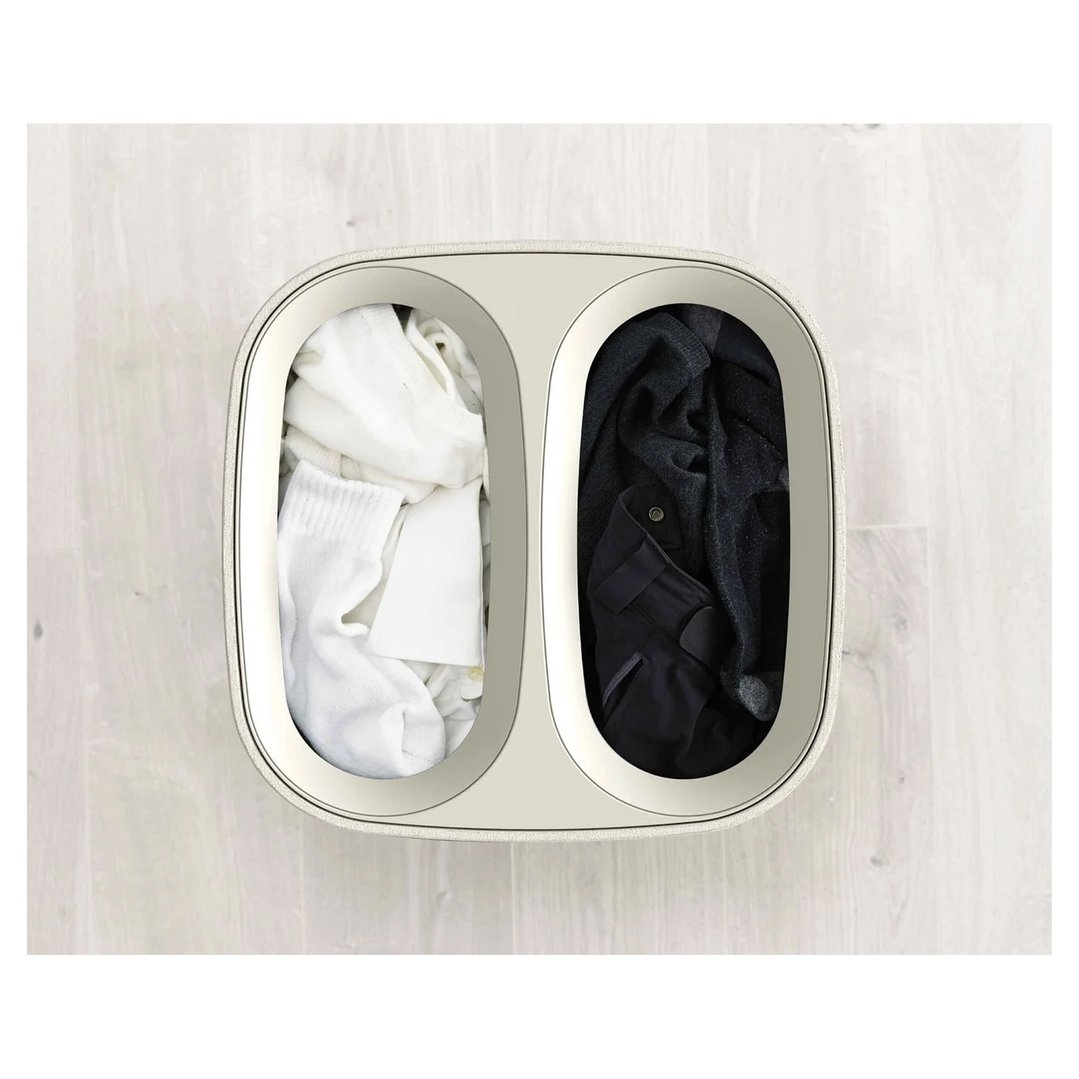 Overhead view of a laundry basket with white and dark clothes on a light floor