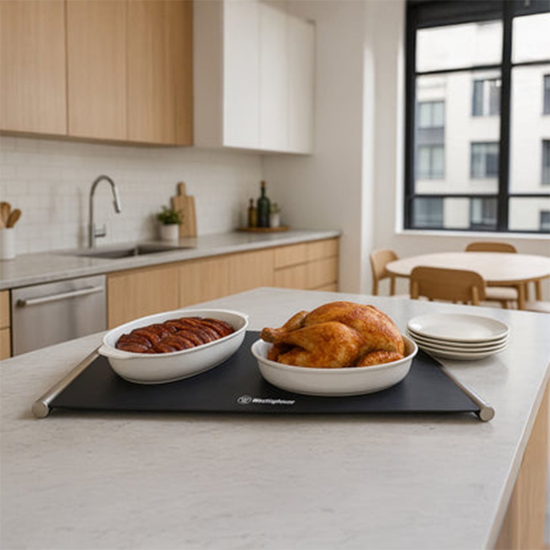 Portable silicone food warmer with roasted chicken and sausages on a kitchen island