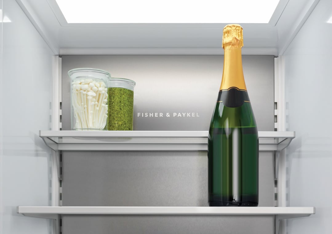 Interior view of a refrigerator with a bottle of champagne and two jars
