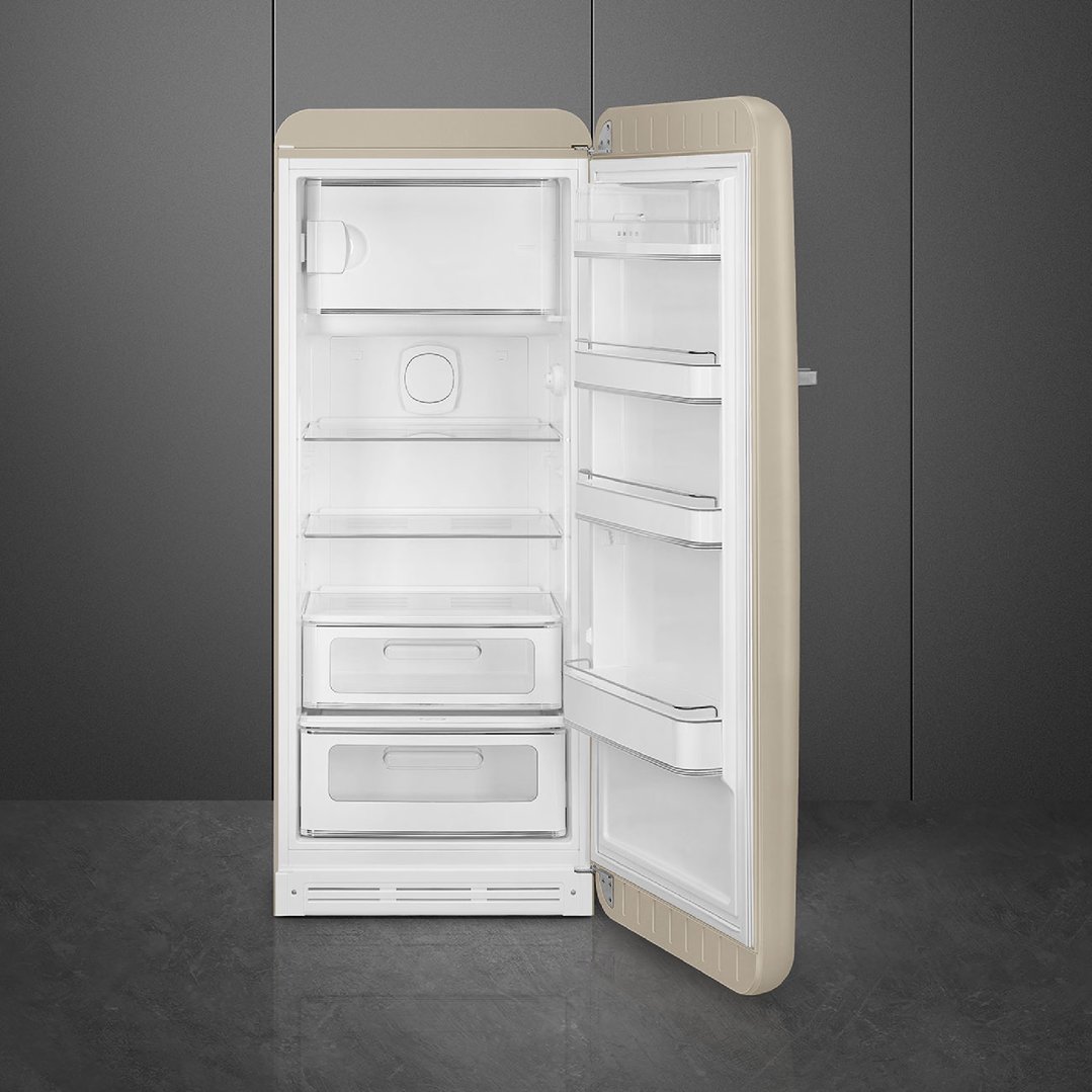 Open beige Smeg refrigerator with interior shelves and drawers in a dark room