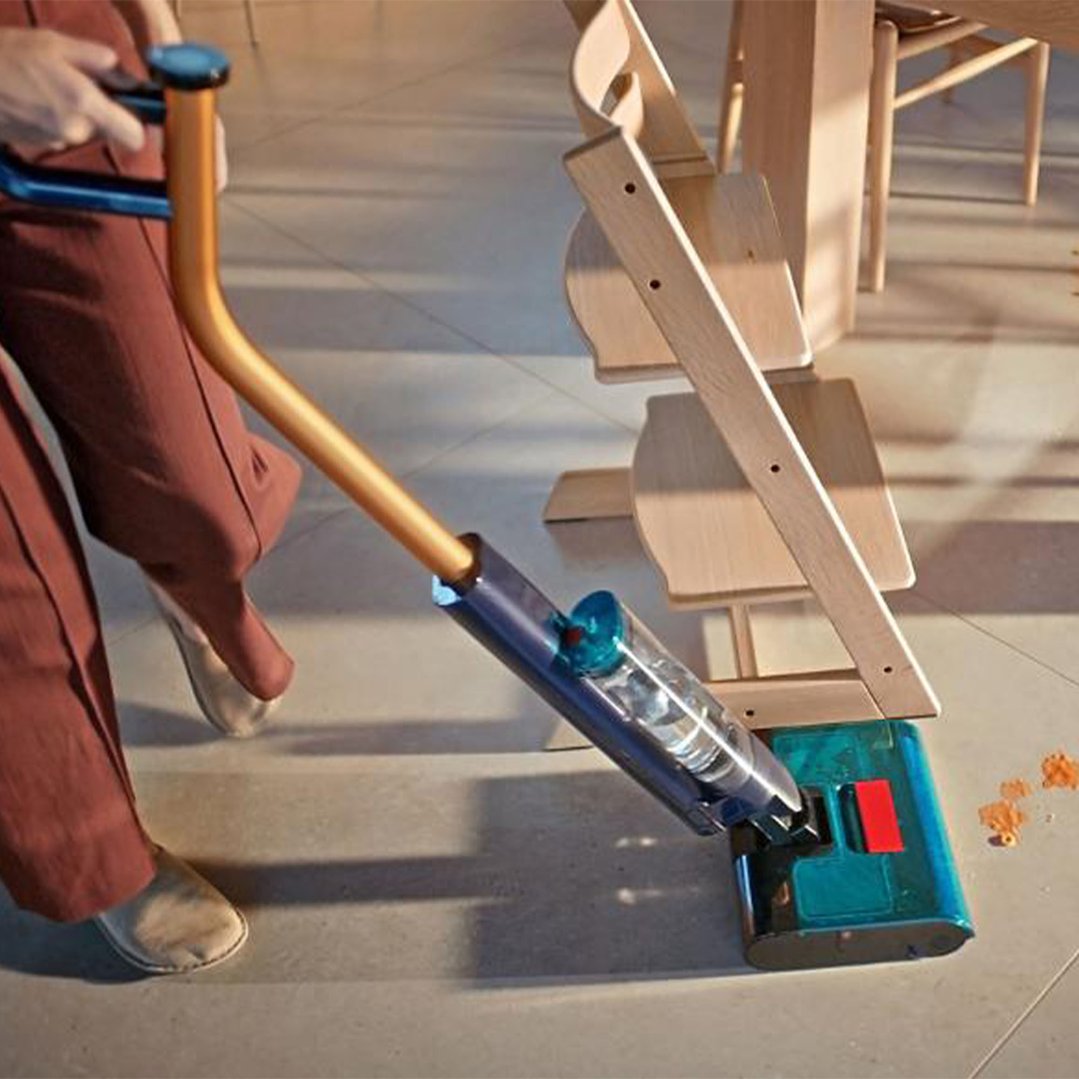 Person cleaning spilled food from the floor with a Dyson hard floor cleaner
