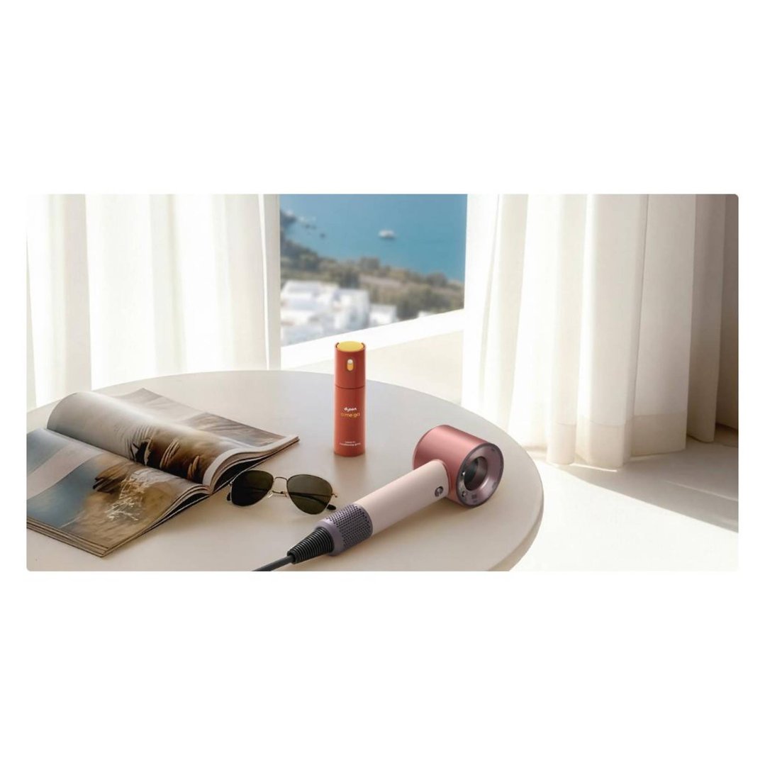 Dyson Supersonic hair dryer, sunglasses, and magazine on a table by a window
