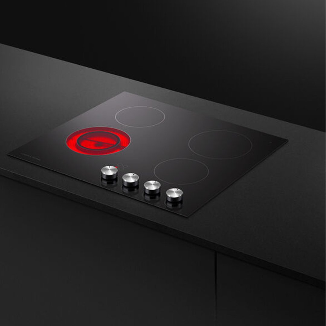 Black electric cooktop with four elements, one glowing red, built into a dark countertop