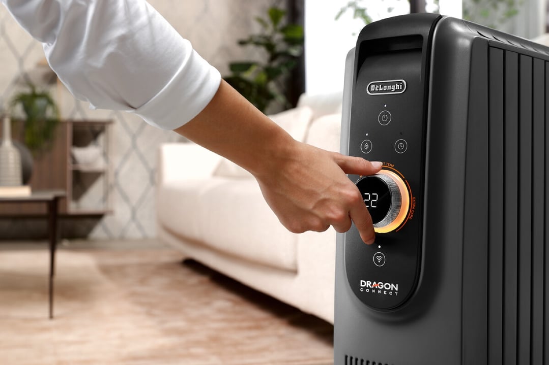 Hand adjusting the settings on a DeLonghi Dragon Connect oil column heater